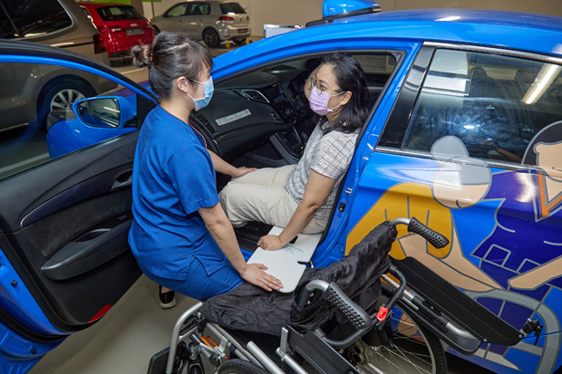  Ms Samantha Ong shows how a patient with an amputation (role-played by SGH Communications Department’s Ms Brenda Ng) can be helped into a taxi from a wheelchair using a transfer board.